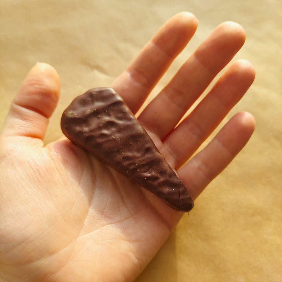 a hand holding a piece of chocolate in it's palm