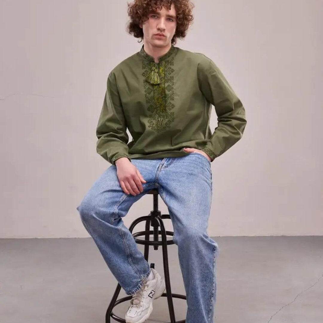 a man sitting on a stool wearing a green shirt