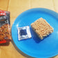 a blue plate topped with a bag of ramen next to a bag of noodles