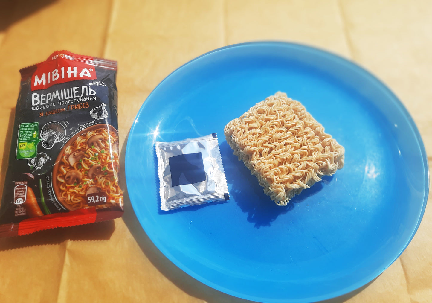 a blue plate topped with a bag of ramen next to a bag of noodles