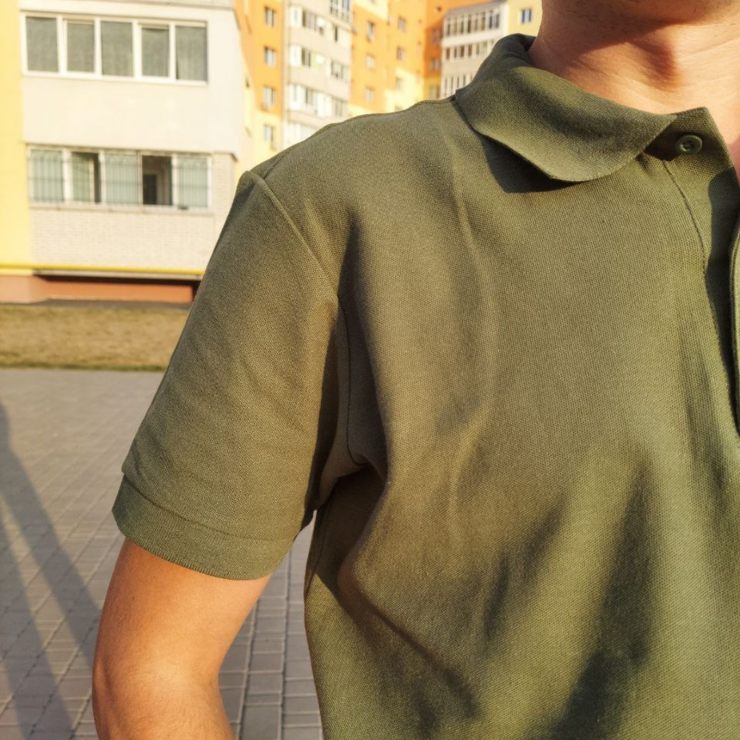 a man in a green shirt holding a cell phone to his ear