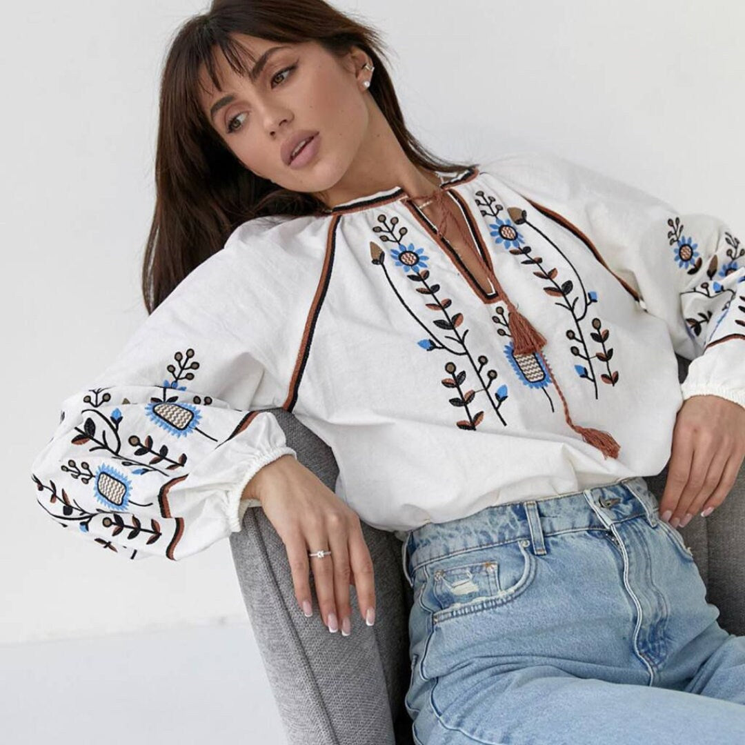 a woman sitting in a chair wearing a white blouse and jeans