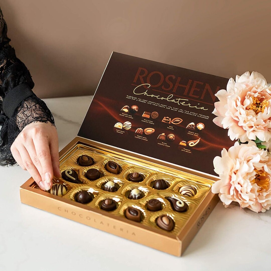 a woman is holding a box of chocolates