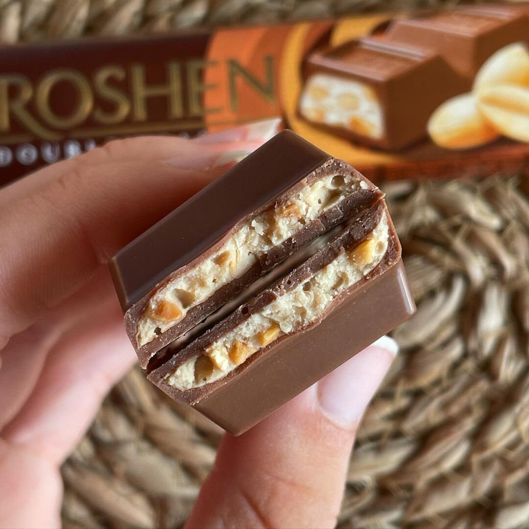 a hand holding a bar of chocolate and nuts