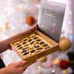 a person holding a box of cookies in front of a christmas tree