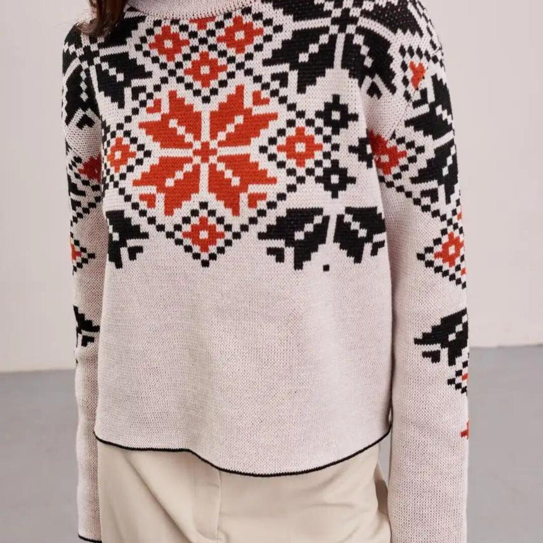 a woman wearing a white sweater with an orange and black pattern