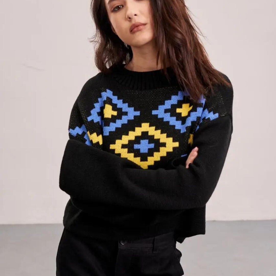 a woman wearing a black sweater with a blue and yellow pattern