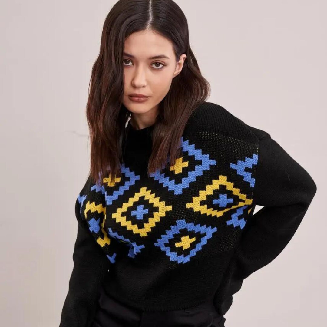 a woman wearing a black sweater with a blue and yellow pattern