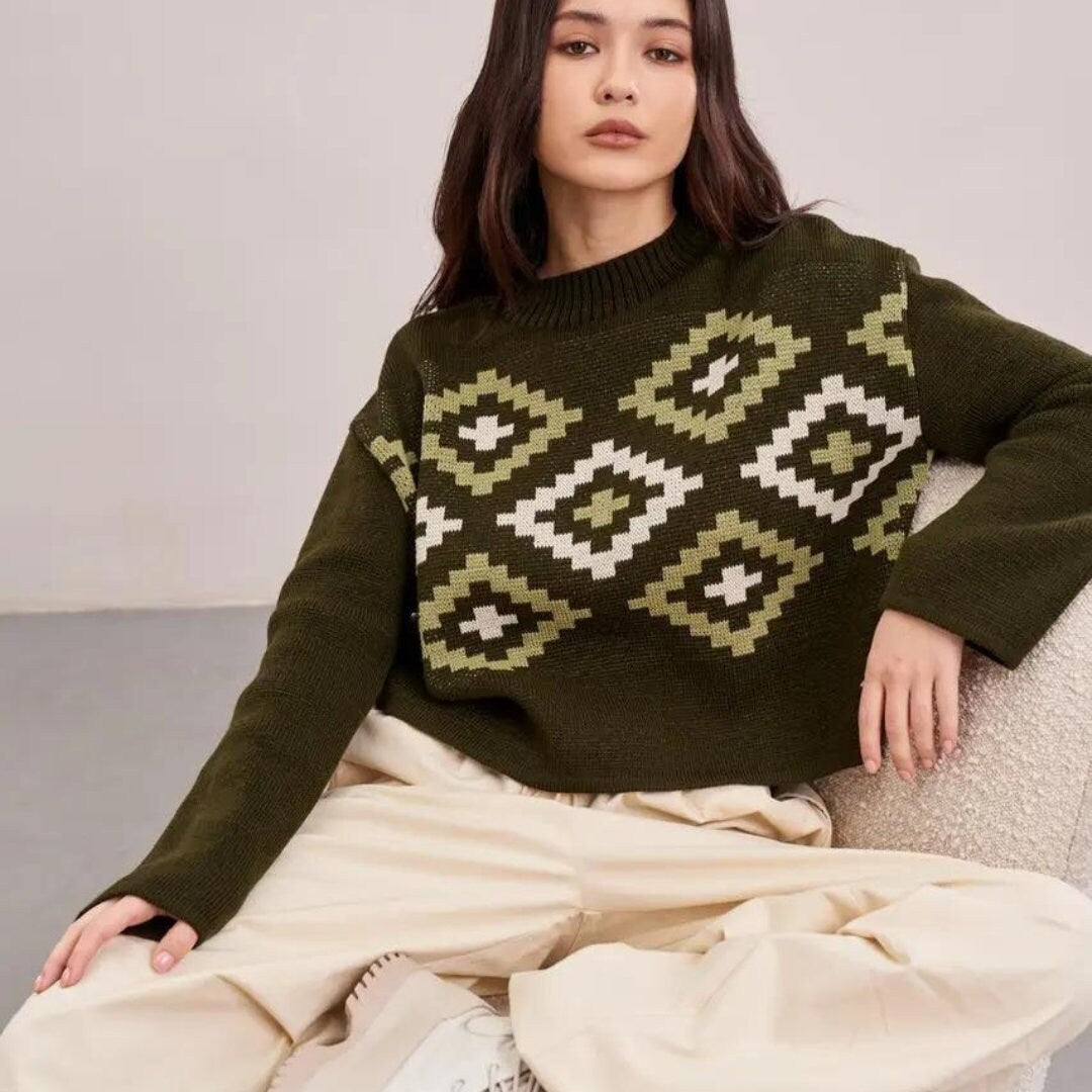 a woman sitting on a chair wearing a green sweater