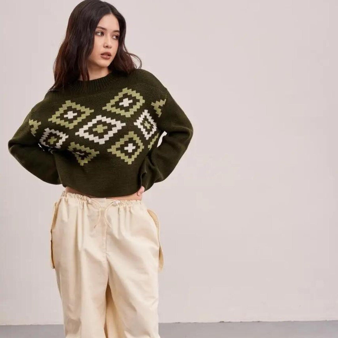 a woman wearing a green sweater and beige pants